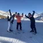 3 students with their arms and ski poles in the air