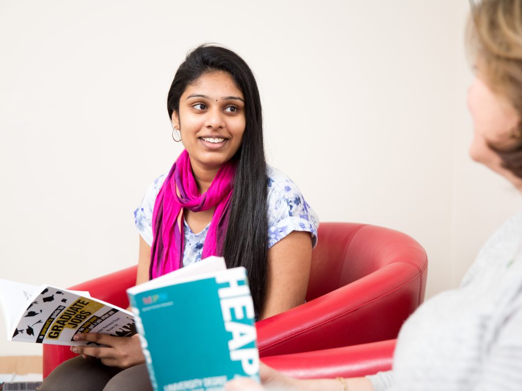 A student reading through a "graduate jobs" booklet