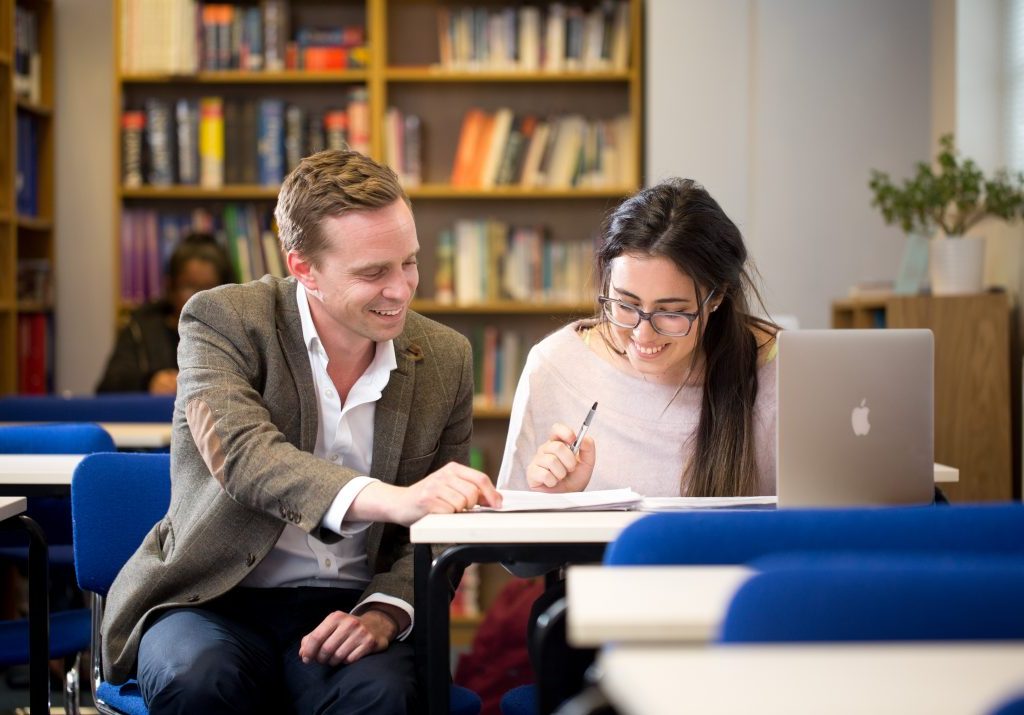 A teacher helping a student in the library