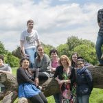 teachers and pupils posing around a big tree branch