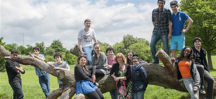 teachers and pupils posing around a big tree branch