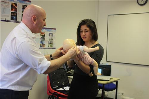 teacher helping pupil hold a fake baby doll