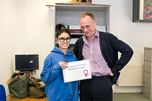 girl stood holding a certificate with her teacher