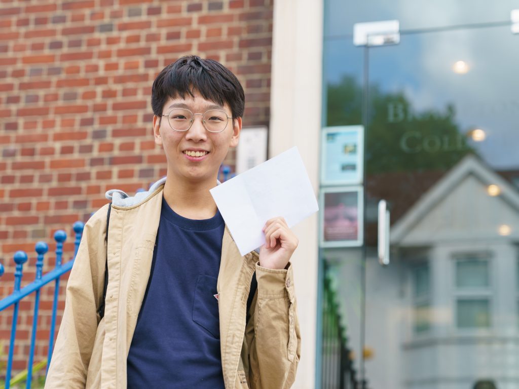 boy holding his a level results envelope