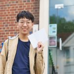 boy holding his a level results envelope