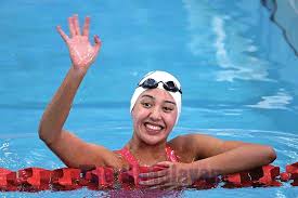 girl in a swimming pool waving