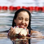 girl in pool with swimming medals