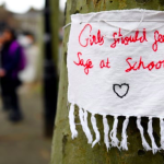 sign on tree with message: girls should feel safe at school