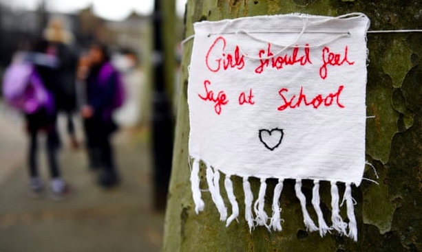 sign on tree with message: girls should feel safe at school
