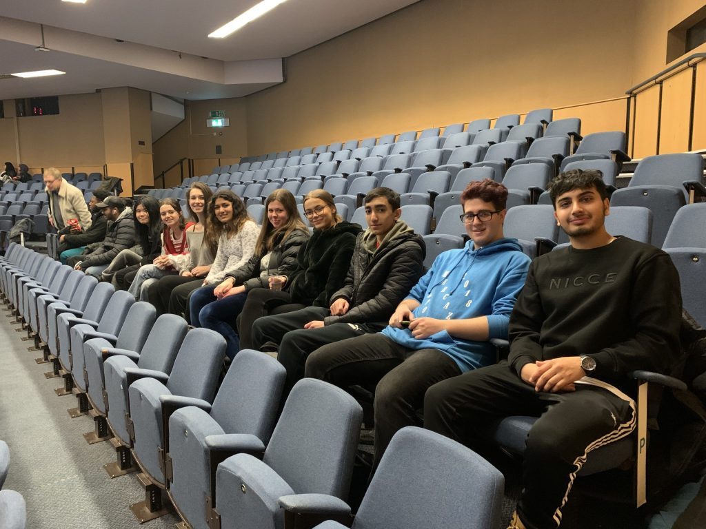 Students smiling as they're sat in an auditorium