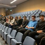 Students smiling as they're sat in an auditorium