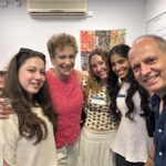 Group of five people posing for a selfie in a classroom, all smiling at the camera.