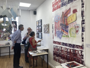 Three adults in a bright gallery observe a large abstract painting on a white wall.